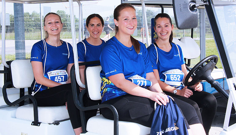 Mitarbeiterinnen von ZIEHL-ABEGG nach einem Lauf Lächelnde ZIEHL-ABEGG Mitarbeiterinnen mit blauem Firmenshirt in einem Golfcart