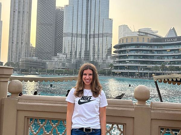 A woman with a blue ZAbroad shirt standing in front of the branch building in Dubai with the logo of ZIEHL-ABEGG in the background