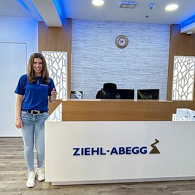 A woman is standing next to the reception of ZIEHL-ABEGG Dubai